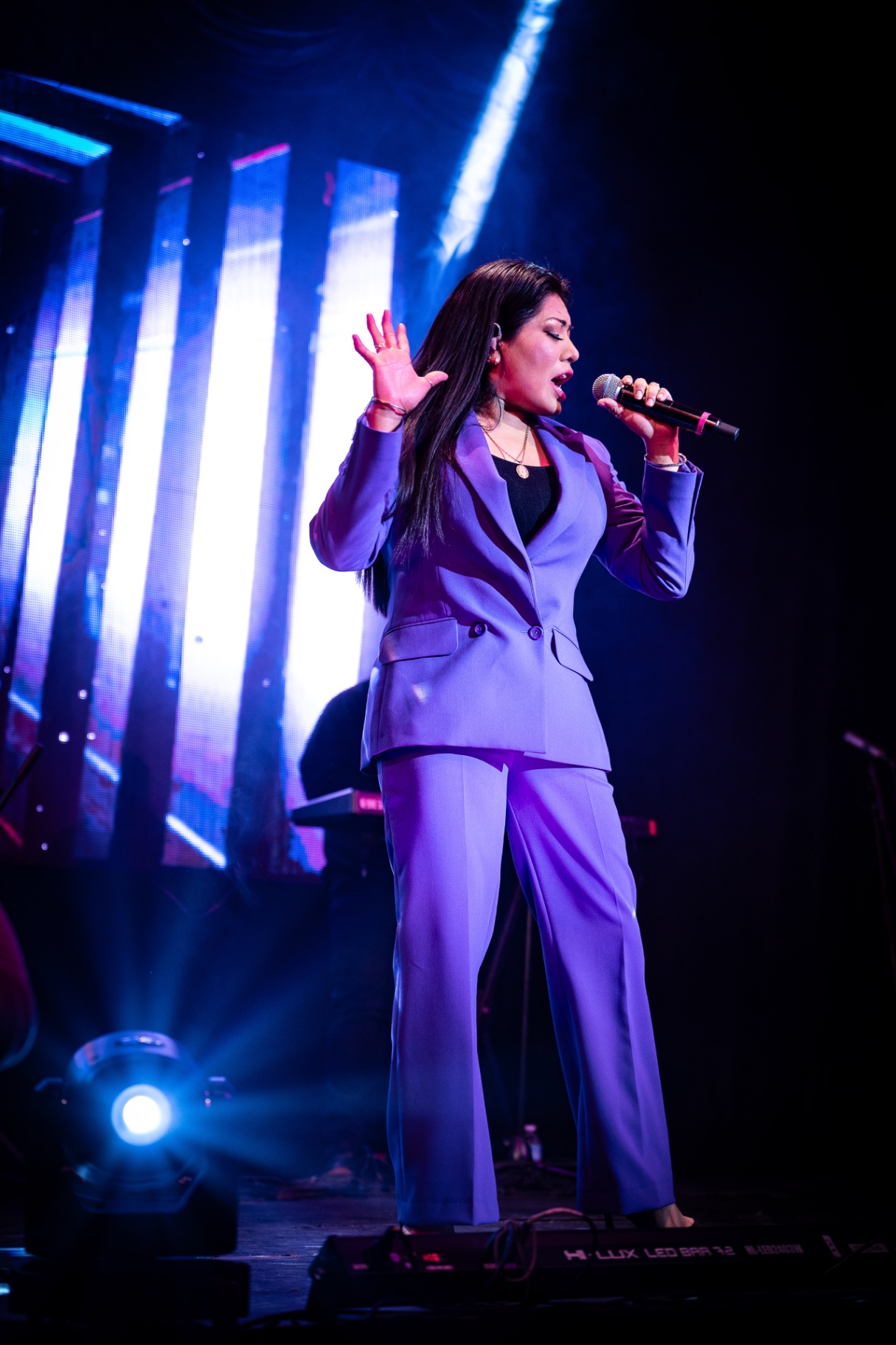 Rosario del Valle cantando con traje lila bajo luces azules